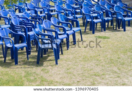 Blue plastic chairs arranged in rows for an outdoor event.