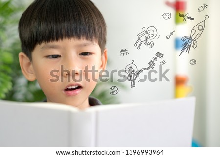 Kids imagination: A little boy having fun reading a book about the outer space, astronauts and planet. Child's brain development - Cognitive skills