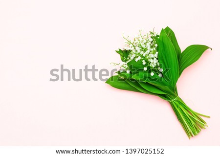 A bouquet of lily of the valley on a light pink background. Spring flowers. Greeting card. Top view