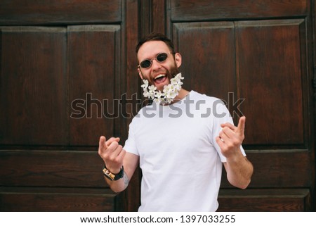 Handsome hipster man in sunglasses with beard of flowers