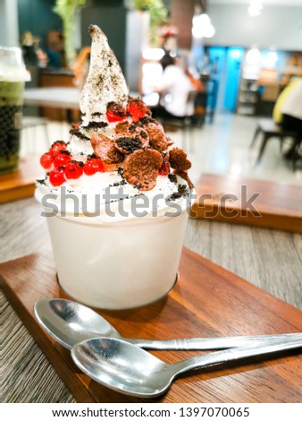 Closed up of Froyo ice cream on top with chocolate powder, red jelly, and cookies in dessert cafe Royalty-Free Stock Photo #1397070065