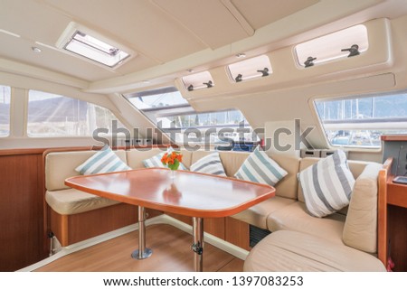 Interior of a stunning modern private sailing catamaran, portraying the saloon with big lounging area with cushions  Royalty-Free Stock Photo #1397083253