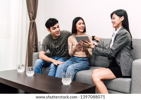 Real estate agent holding document and talk with young couple in a house for sale. business and real estate concept