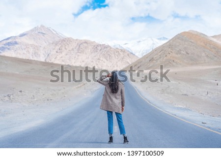 Young asian woman traveler wearing coat enjoying the view of Himalaya mountain background against blue sky in Leh, Ladakh, India. Enjoying holidays