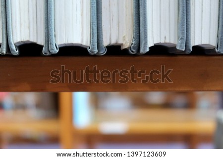 Series of  hard cover binding books on library shelf  - with blurred background for copy space. Concept of academic student reading / reference researching.