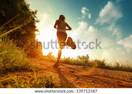 Young lady running on a rural road during sunset Royalty-Free Stock Photo #139712587