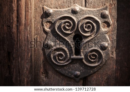 Vintage metal keyhole decorative element on weathered wooden surface