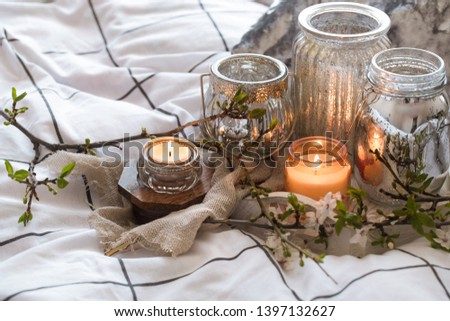 Home interior. Cozy still life with different candles in bed and spring flowers