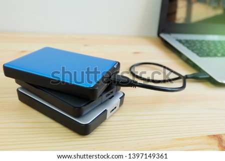 Many portable external hard Drives connect to laptop computer on wooden background