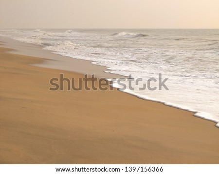 In the morning, the sea water shore gently into a white bubble, rising to the beach with clear yellow sand. Photo for background.