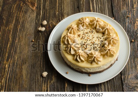 Homemade cheesecake with peanut flavor and coffee cream on white plate on dark wooden background