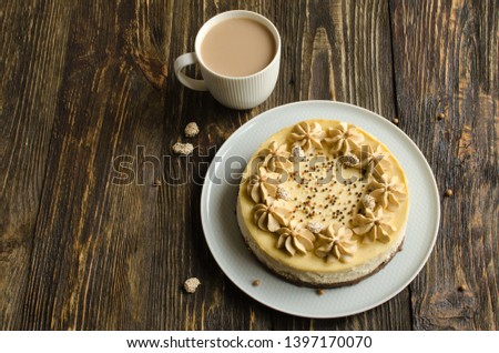 Homemade cheesecake with peanut flavor and coffee cream on white plate and cup of coffee on dark wooden background