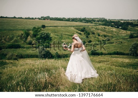 bride with a bouquet of flowers walking in the field in summer