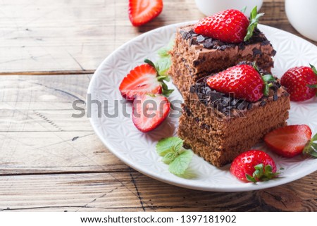 Chocolate truffle cake with strawberries and mint. Wooden table Copy space