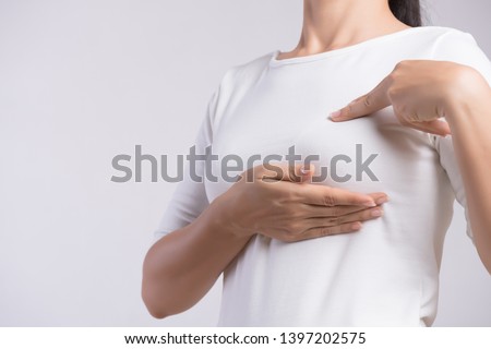 Woman hand checking lumps on her breast for signs of breast cancer on gray background. Healthcare concept. Royalty-Free Stock Photo #1397202575