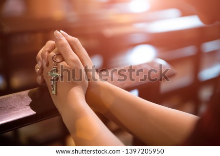Woman hand holding rosary against cross and praying to God at church. Royalty-Free Stock Photo #1397205950