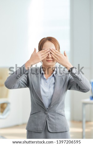 Portrait of young businesswoman standing in formal wear and closed her eyes with hands at office