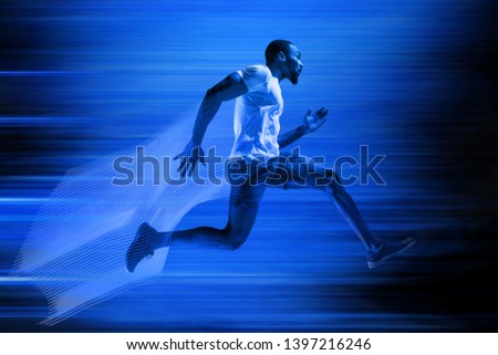 Young african-american man running isolated on blue studio background. One male runner or jogger. Silhouette of jogging athlete with shadows in neon light. Movement or motion. Creative collage.
