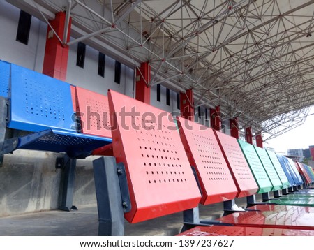 View of stadium with empty seat. Colorful seat in soccer stadium when holiday. Blue, green and red iron seats. Landscape of free arena seating.  