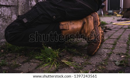 Spring cleaning- Garden -person removing weeds with a closeup on working boots and pants