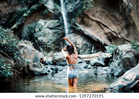 Cheerful young woman in bikini relaxing in summer on waterfall background, People freedom style. Summer concept