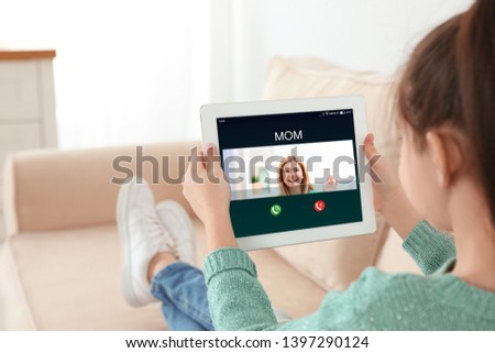 Closeup view of little girl using tablet for conversation with mother via video chat at home 