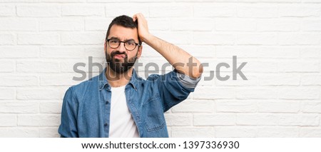 Handsome man with beard over white brick wall with an expression of frustration and not understanding Royalty-Free Stock Photo #1397336930