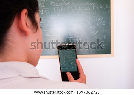 teenager taking picture with the cellphone to the class blackboard