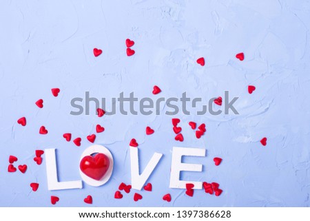 Word love from white wooden letters and little red hearts on blue textured  background. Top view. Flat lay. Place for text.
