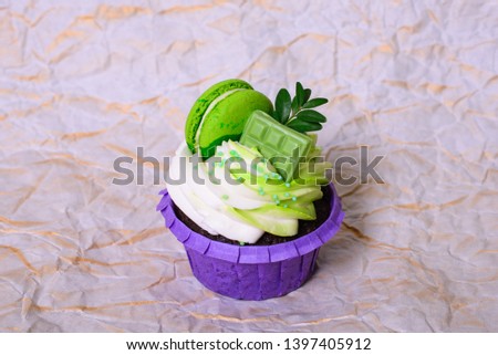 Cupcake with whipped cream, chocolate bar, decorated macaroons on crumpled paper. Picture for a menu or a confectionery catalog. with space for text.