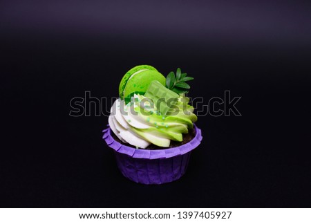 Cupcake with whipped cream, chocolate bar, decorated macaroons on black background. Picture for a menu or a confectionery catalog. with space for text.