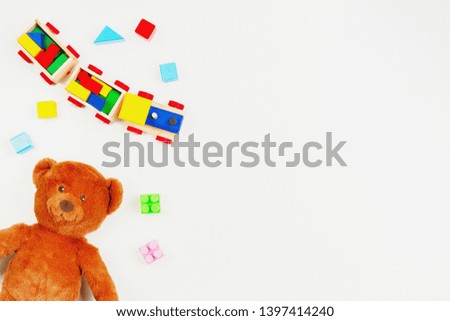 Baby kids toys background. Teddy bear, wooden train, colorful bricks on white table