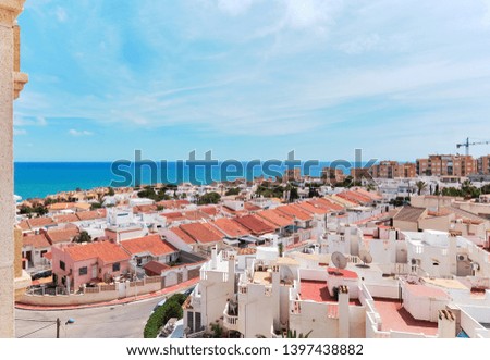 Above view rooftops of spanish pretty residential houses near the Mediterranean Sea, turquoise water, horizon over the sea, clear blue sky in Torrevieja. Costa Blanca, Province of Alicante, Spain