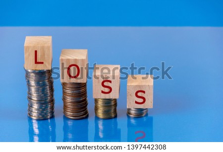 Wooden cube text "LOSS" with stack of coin on table with reflector. Stock loss concept. Using copy space for stock investment concept.