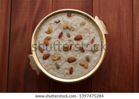 payasam-vermecelli payasam which is garnished with dry fruits placed in a brass vessel with wooden brown background in south indian style