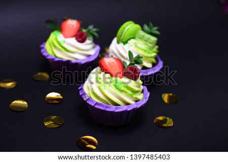 cupcakes with whipped cream decorated chocolate bar, strawberry ,macaroons on black background. Picture for a menu or a confectionery catalog. with space for text.