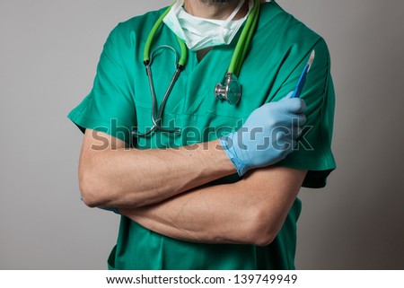 Physician in green uniform holding a surgical knife