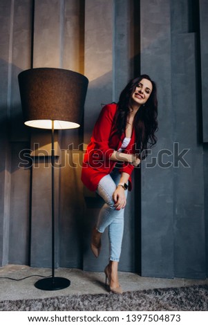 Photo session of a young brunette in jeans and a red jacket.