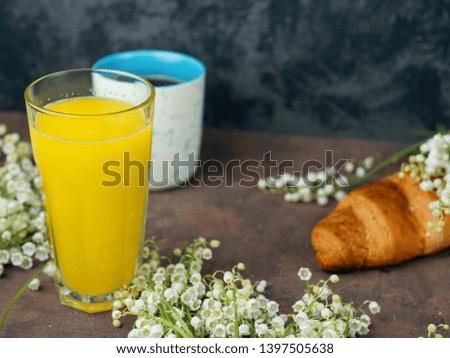 A Cup of coffee, a glass of orange and a croissant for Breakfast. Bouquet of Lily of the valley