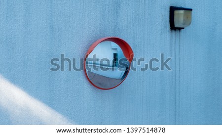 Red Blind corner mirror mounted on a concrete wall