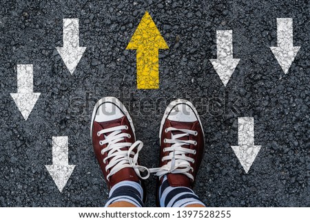man shoes asphalt and opposing direction arrows on asphalt ground, personal perspective footsie concept for finding your own way Royalty-Free Stock Photo #1397528255