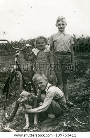 Vintage photo of three children with a dog and a bike - thirties