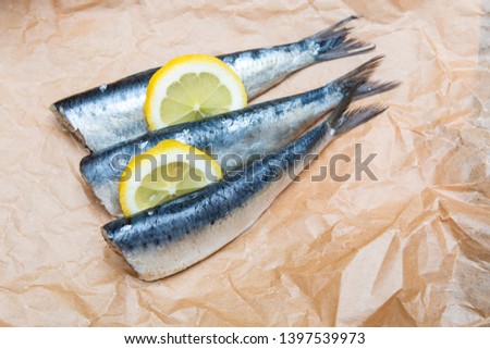 fresh sardines and lemons on brown cooking parchment Royalty-Free Stock Photo #1397539973
