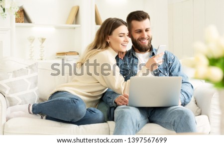 Surfing Internet. Young Couple Relaxing With Laptop And Smartphone, Sitting On Sofa Royalty-Free Stock Photo #1397567699