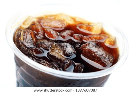           Ice cubes with sugar granules melting in iced coffee in plastic cup.                      