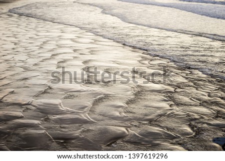 Water textures on the surf and sand of the beach