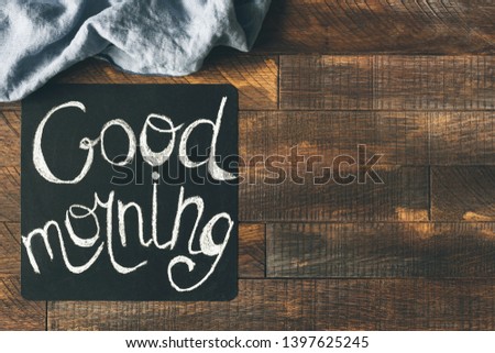 Good morning greeting on blackboard on a wooden table background. Cheerful morning greeting. Design mock up
