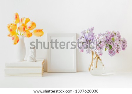 Home interior with decor elements. White frame, branches of lilac in a vase, interior decoration