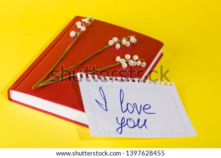 Red notepad with lily of the valley flowers and a leaflet that says I love you