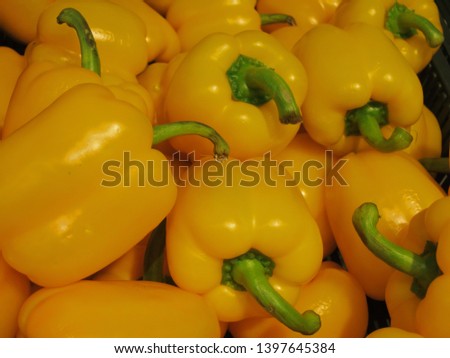 Background of yellow peppers with green tails close-up